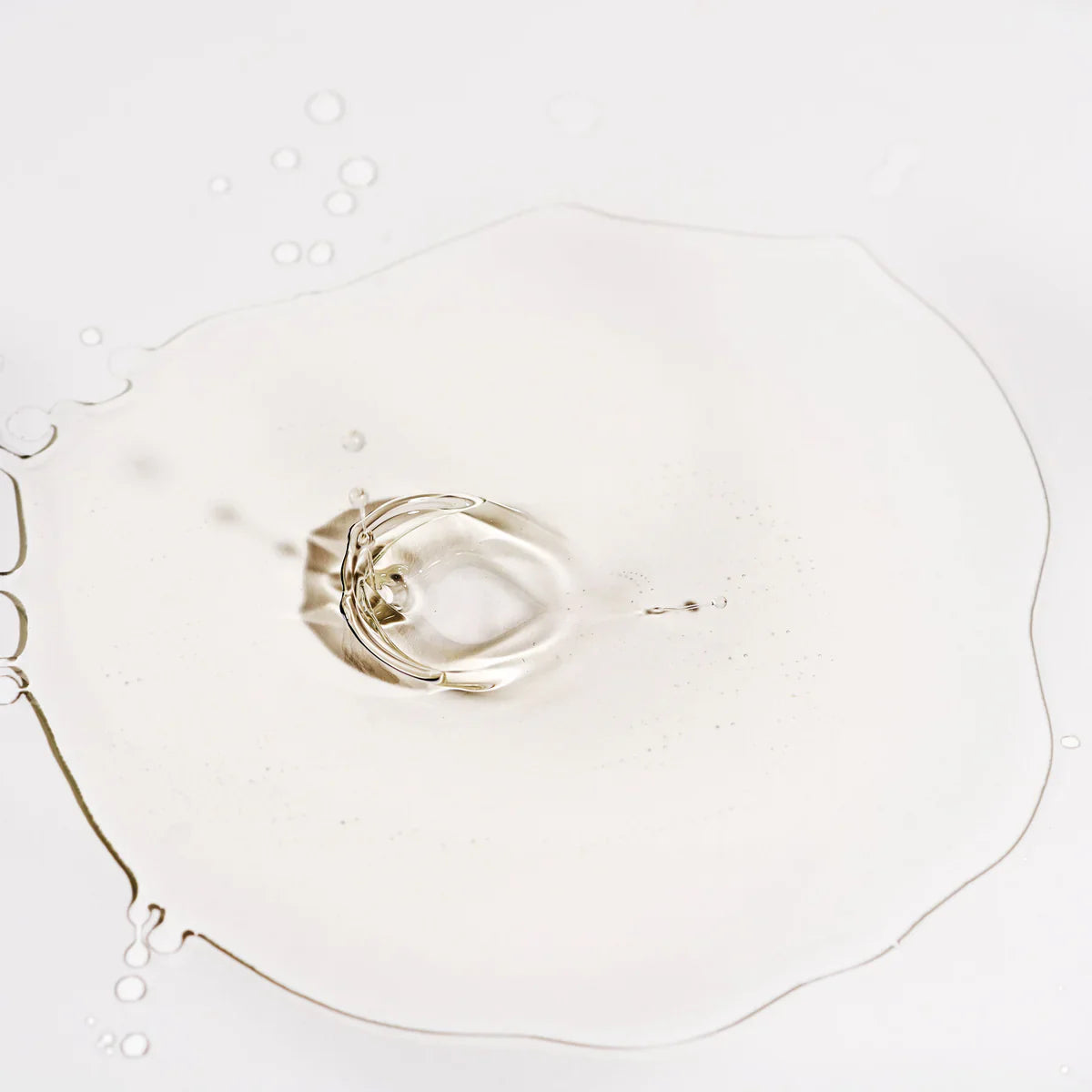 Texture sérum visage transparent en goutte éclaboussée sur fond blanc, formule légère