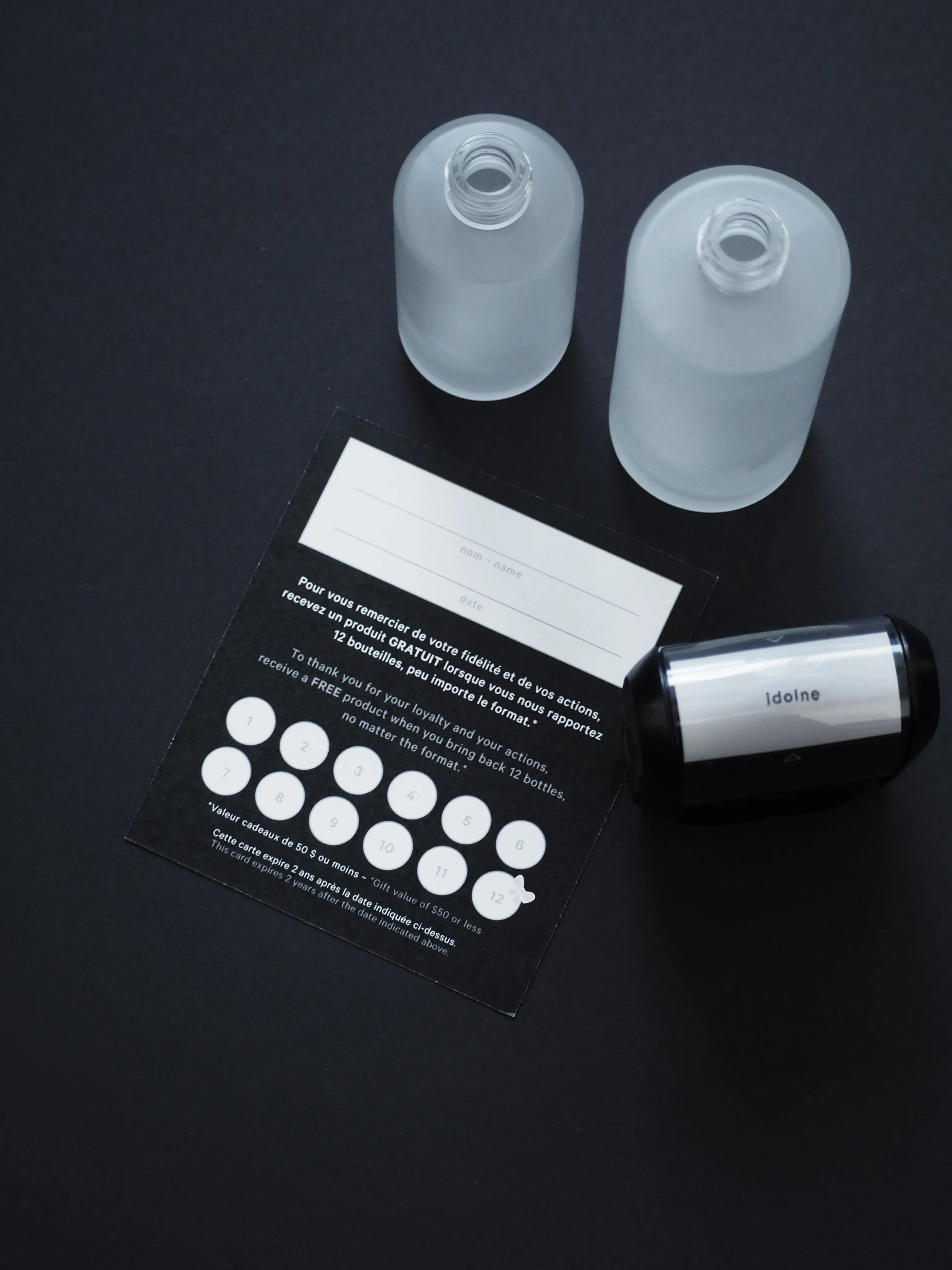 Idoine eco-friendly recycling program with frosted glass bottles, loyalty card, and stamp system encouraging customers to return empty containers