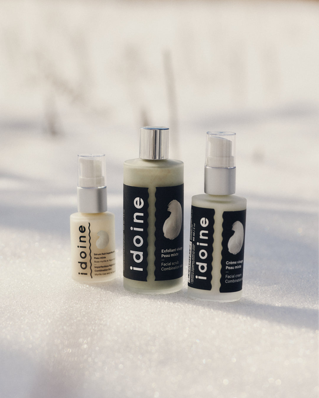 Idoine Bio anti-aging elixir serum with rosehip and Italian helichrysum, shown in a yellow glass bottle held outdoors in natural light.